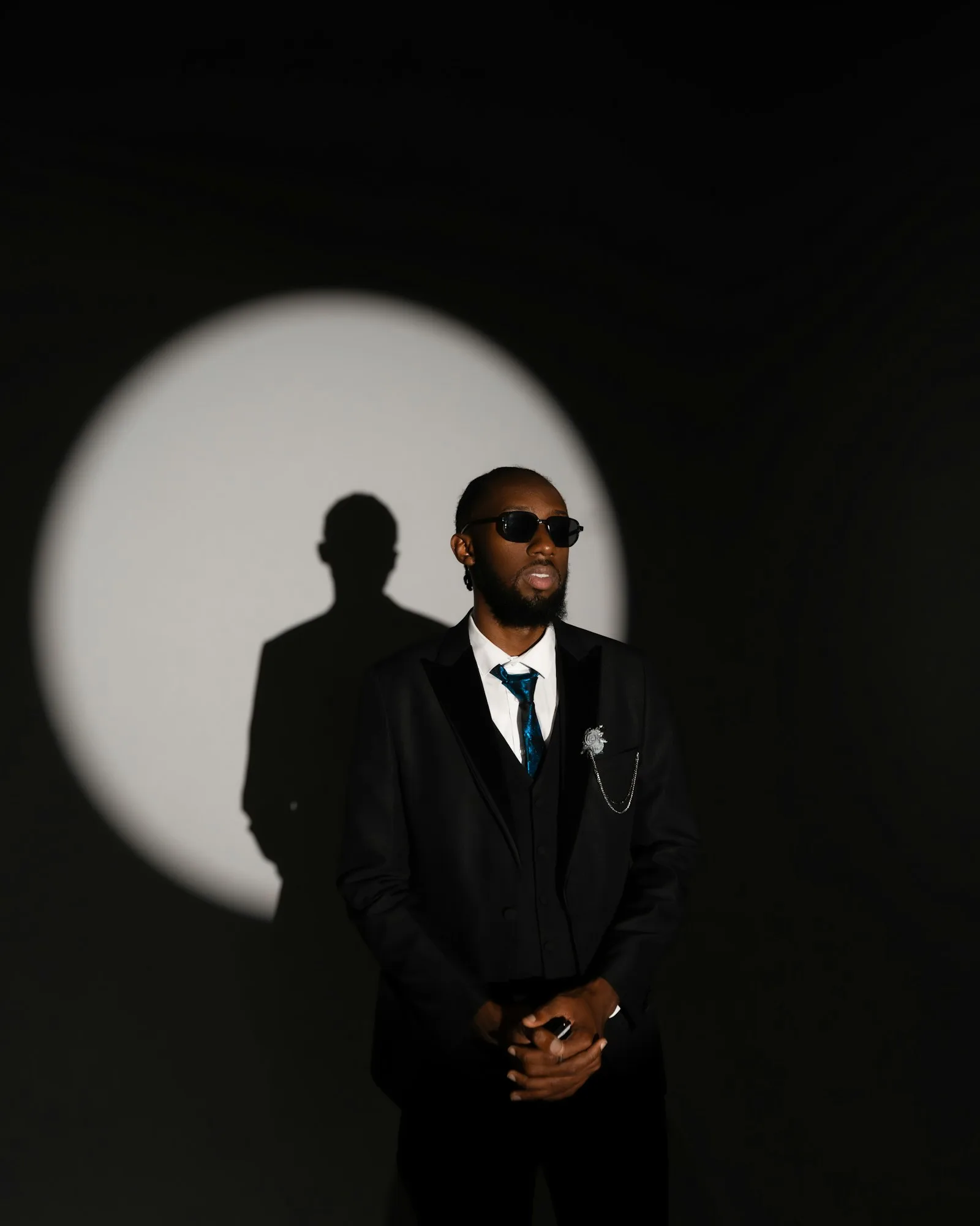 Confident man in formal black attire under dramatic lighting